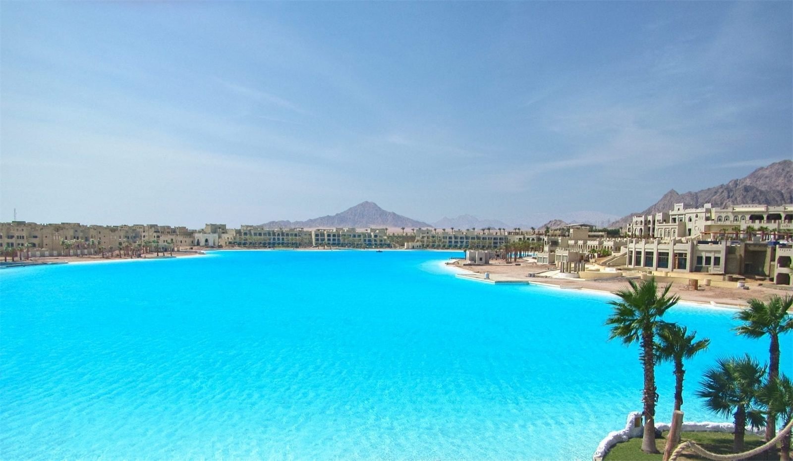 Turquoise lagoon with resort buildings and mountains behind
